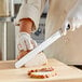 A person using a Choice Classic Granton Edge Rounded Carving Knife to slice meat.