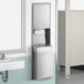 A Lavex stainless steel paper towel dispenser with a waste receptacle above a white sink.