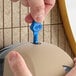 A person's hands using a blue Lavex Pro dispenser key to open a dispenser.