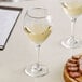 A plate of food and two Acopa Bouquet wine glasses on a table in a winery cellar.