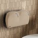 A Lavex Pro Sand double-roll jumbo toilet tissue dispenser mounted on a tan tile wall.