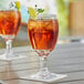 Two Acopa glass goblets with drinks on a table.