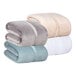 A stack of three Berkshire Hospitality Serasoft+ king size blankets in three different colors.