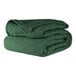 A stack of green Berkshire Hospitality bedspreads.