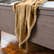 A Berkshire Hospitality VelvetLoft Almond polyester throw blanket draped over a bed.