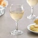 An Acopa all-purpose wine glass filled with white wine next to a plate of food.