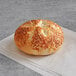 A Tribute Baking Company Asiago cheese bagel on a napkin.