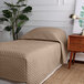 A twin size bed made with a tan Berkshire Hospitality diamond quilt fitted coverlet.