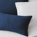 A blue and white Berkshire Hospitality knit2fit diamond throw pillow on a bed.