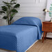 A Berkshire Hospitality twin size blue quilted fitted coverlet on a bed.