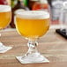 Two Acopa schooner glasses filled with beer on a table.