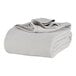 A folded Berkshire Hospitality king size gray cotton blanket.