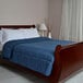 A bed made with a blue Berkshire Hospitality twin size blanket and white pillows.