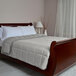 A twin size bed with a white Berkshire Hospitality down alternative blanket and pillows on it.