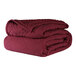 A stack of burgundy Berkshire Hospitality CozyCare Classic twin size fitted coverlets.