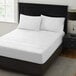 A white Berkshire Hospitality quilted mattress pad on a bed with white sheets.