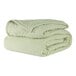 A stack of Berkshire Hospitality CozyCare bedspreads in spa green.