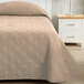 A tan Berkshire Hospitality CozyCare Lamb's Wool bedspread on a bed with a pillow and a vase on a nightstand.