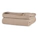 A stack of beige Berkshire Hospitality Microfleece blankets.