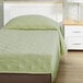 A twin size bed made with a spa green Berkshire Hospitality CozyCare fitted coverlet.