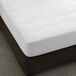 A Berkshire Hospitality white quilted mattress pad on a mattress.