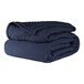 A stack of four navy blue Berkshire Hospitality CozyCare bedspreads.