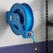A Regency blue powder-coated steel hose reel attached to a wall.