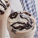 Two glasses of chocolate milkshakes with whipped cream and Ghirardelli chocolate syrup.