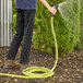 A person using a Regency polyester braid reinforced rubber washdown hose to water a garden.