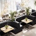 A room in a restaurant with black leather corner booths and tables.