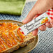 A hand holding a Bonne Maman Apricot Preserves packet over a piece of bread.