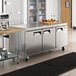 An Avantco stainless steel undercounter refrigerator on a large stainless steel kitchen counter.