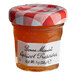 A Bonne Maman mini jar of apricot preserves on a table with a red and white checkered tablecloth.