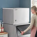 A woman opening the Hoshizaki KMD-505MWJ water cooled ice machine.
