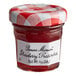 A Bonne Maman mini jar of strawberry preserves with a white label and red and white checkered lid on a table.