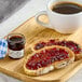 A plate of toast with Bonne Maman Muscat Grape Jelly on it next to a cup of coffee on a table.
