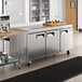 An Avantco stainless steel worktop refrigerator on a large counter top in a professional kitchen.