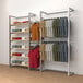 A white wall-mounted retail display with clothes hanging on it.