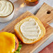 A cheeseburger with Sir Kensington's Classic Mayonnaise on a cutting board.