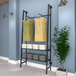 A wall-mounted Econoco A-frame retail clothing rack with shelves and faceouts holding clothes.
