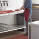 A man in a red apron and gloves using a Regency adjustable undershelf for a work table in a professional kitchen.