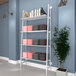 An Econoco white wall-mounted shelving unit with books and a plant on it.