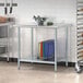 A galvanized steel undershelf on a metal work table with bowls of vegetables on it.