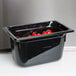 A black Vollrath Super Pan with red tomatoes inside on a counter.