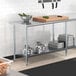 A Steelton adjustable galvanized steel undershelf on a work table in a professional kitchen.