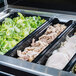 A Vollrath black polycarbonate food pan with lettuce, meat, and other food.