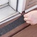 A person using Gorilla Anti-Slip Tread Tape to cover a door.