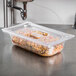 A Vollrath clear polycarbonate food pan filled with food on a counter.