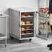 A man standing in front of a metal cabinet with bread in a bakery display.