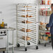 A man standing in front of a Regency sheet pan rack filled with bread.